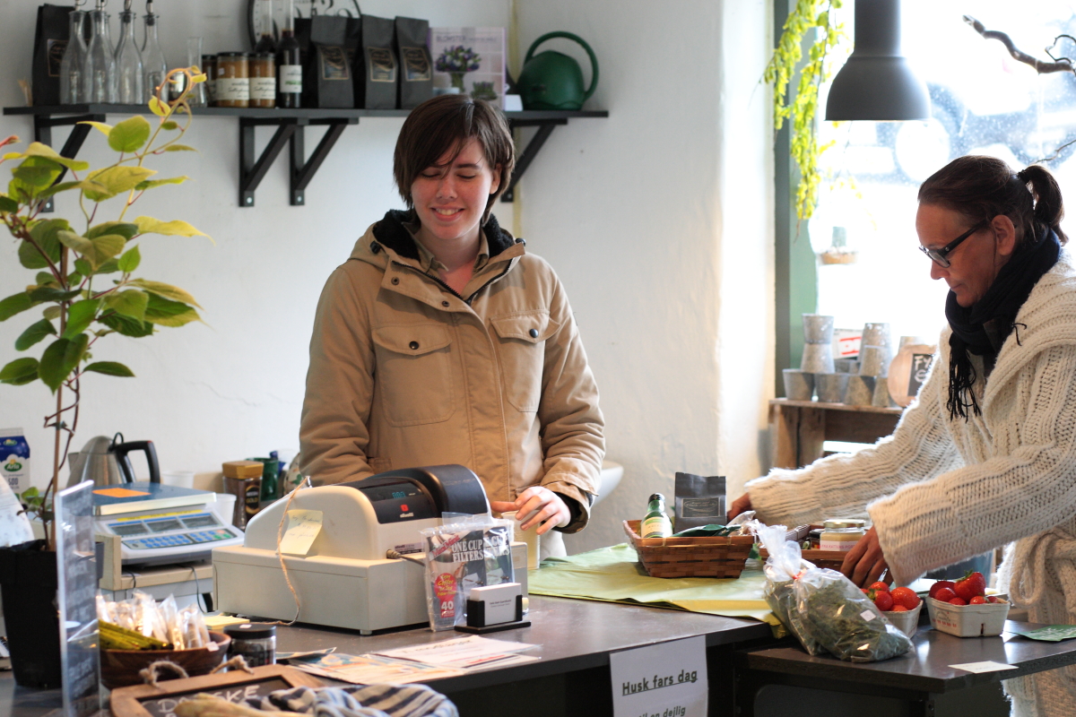 Ekspedient sælger grøntsager i gårdbutik